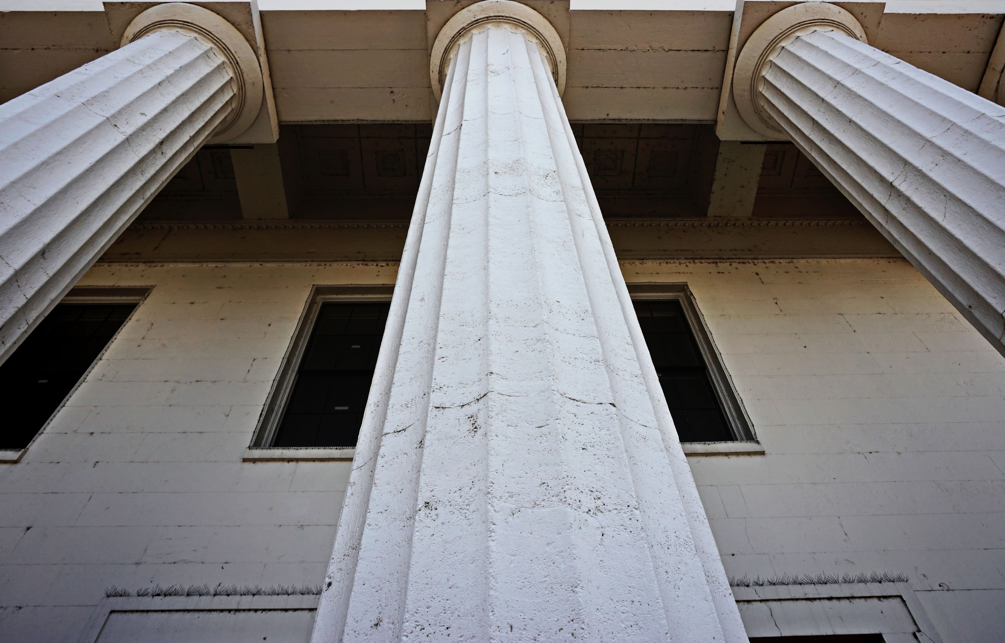 a tall white building with two windows and two columns